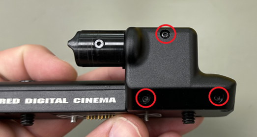 A hand holding a black device with red circles

Description automatically generated